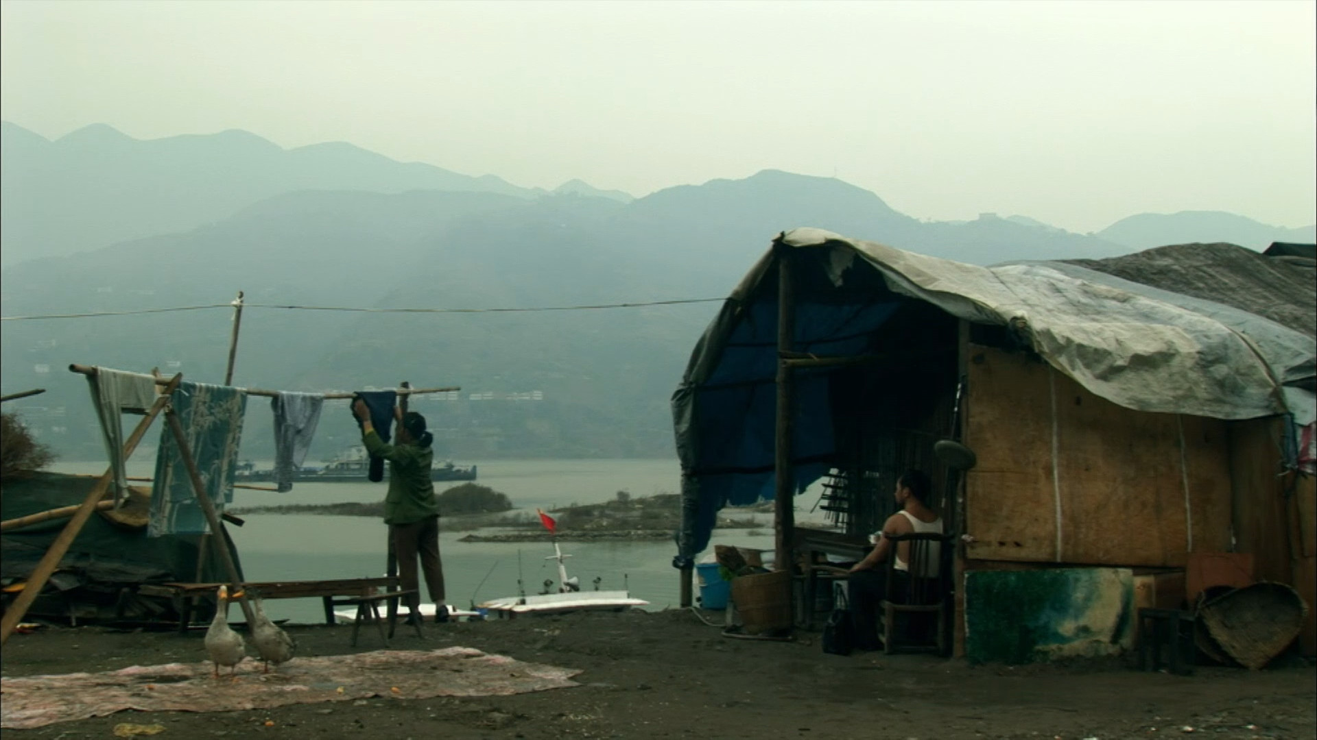 Woman hanging laundry outside of her hut overlooking the river